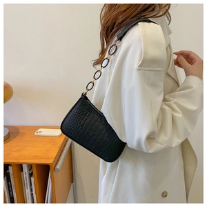 Détail d'un sac à bandoulière noir texture crocodile avec boucles dorées élégantes