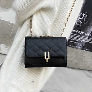Detail of black quilted chain bag with gold H-buckle worn by a model in casual style