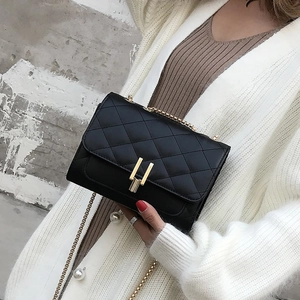 Close-up of classic quilted chain bag with gold metal lock on a beige cardigan