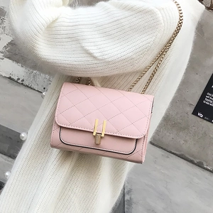 Detail of pink quilted crossbody bag featuring a golden U-shaped clasp and chain strap