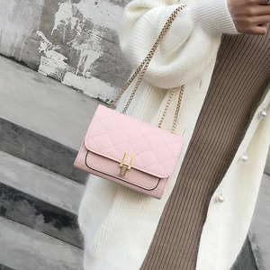 Detail of light pink quilted chain bag with a gold metal clasp and cross stitching