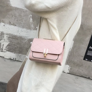 Detail of pink quilted chain crossbody bag with golden metal buckle on a model