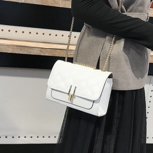 Side view of white quilted chain bag with gold buckle on a model's shoulder