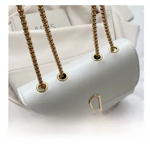 Detail shot of white leather bag featuring gold hardware eyelets and chunky chain strap