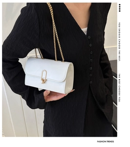 Detail of white leather shoulder bag with gold chain strap and U-shaped metal buckle