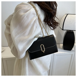 Détail d'un sac bandoulière noir en cuir avec fermoir doré et bandoulière en chaîne