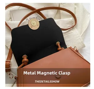 Detail view of the brown leather crossbody bag featuring a durable magnetic snap closure