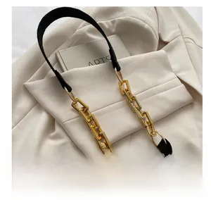 Detail of comfortable black leather shoulder strap with gold metal links on a textured bag