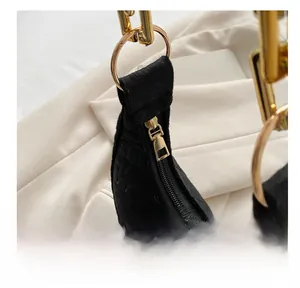 Detailed view of crocodile embossed leather and smooth golden metal zipper on black crescent bag