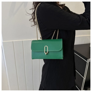Détail du sac bandoulière en cuir vert émeraude avec fermoir doré et bandoulière chaîne