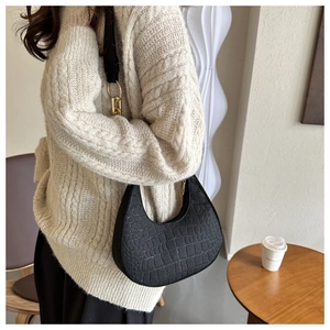 Close-up of black crocodile embossed crescent shoulder bag with golden hardware