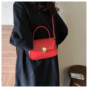 Side view of a bright red leather vintage crossbody bag worn with a black coat