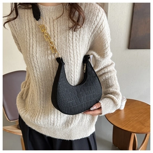 Detail of black crocodile embossed half-moon bag with golden chain and zip closure