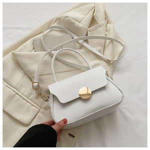 Detail of white leather shoulder bag featuring a circular gold metal magnetic buckle closure