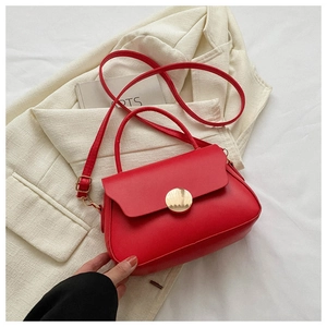 Close-up of matte red PU leather crossbody bag featuring a golden circular magnetic clasp