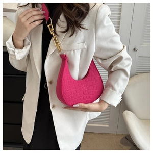 Detail of rose pink crescent bag with faux crocodile texture and chunky gold chain