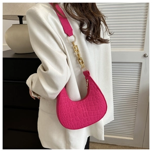 Detailed view of magenta faux crocodile leather underarm bag with gold chain strap