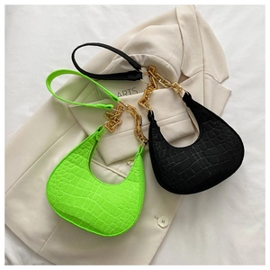 Detail of neon green and black croc-effect underarm bags with gold chain and strap