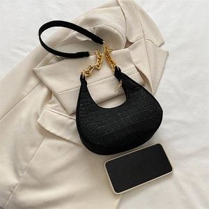 Detailed top view of black croc-effect crescent bag with chunky gold chain and strap