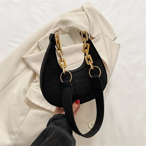 Detail of black faux crocodile leather underarm bag with gold chain and fabric strap