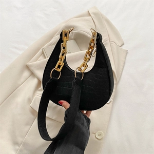 Detail of black crescent shoulder bag featuring crocodile pattern and gold chain strap