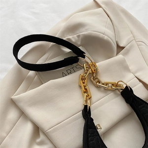 Close-up of black embossed felt underarm bag with gold metal chain strap and shoulder pad