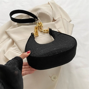 Detail of black faux crocodile skin shoulder bag featuring a chunky gold chain strap