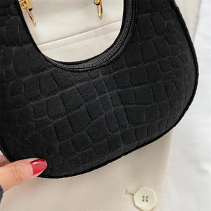 Close-up of black crocodile pattern faux leather on a crescent underarm handbag