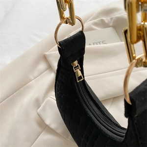 Macro shot of black crocodile embossed crescent bag with golden chain and zipper