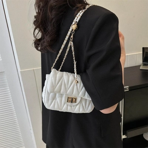 Sac bandoulière blanc matelassé avec chaîne dorée et boucle sphérique sur blazer noir