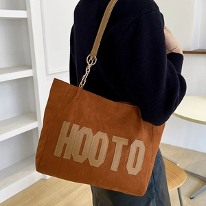 Brown wool tote bag with large HOOTO letters and leather strap worn by a model