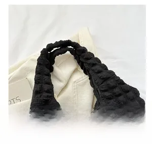 Close-up of comfortable handle on black bubble textured fabric tote bag with pleats