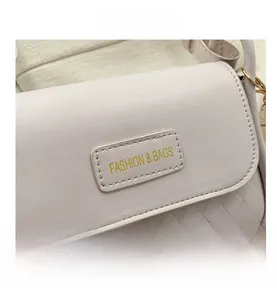 Detail of beige faux leather crossbody bag with quilted texture and fashion label