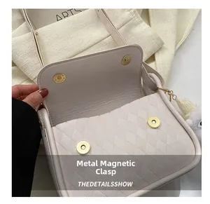 Detail view of double golden magnetic buckles and quilted texture on light beige bag