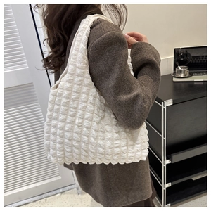 Détail du sac blanc à texture bulle avec matelassage plissé porté par un mannequin