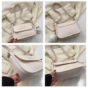 Detail der cremeweißen Stepptasche mit goldener Plakette und flauschigem Monster-Anhänger