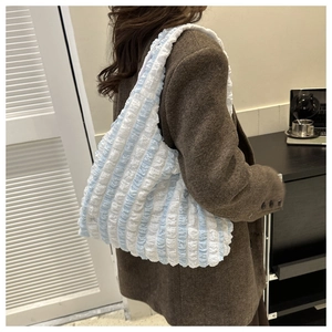 Detail of blue and white striped tote bag with textured fabric on model shoulder