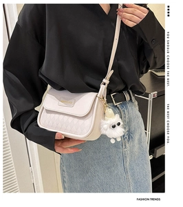 Fashionable beige quilted crossbody bag with golden hardware and plush ball keychain detail