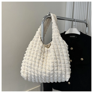 Detail of white popcorn fabric texture on a large capacity pleated shoulder tote bag