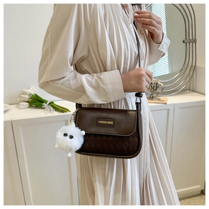 Detail einer braunen PU-Satteltasche mit Webstruktur und goldenem Fashion-Logo