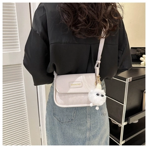 Modische beige PU-Satteltasche mit Rautensteppung und einem flauschigen Monster-Anhänger