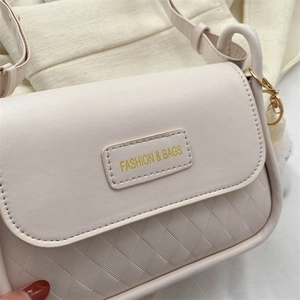 Dettaglio borsa a tracolla beige con motivo a rombi e logo metallico fashion elegante
