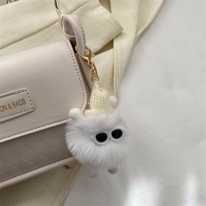 Portachiavi mostro in peluche bianco con berretto e gancio dorato su borsa in pelle