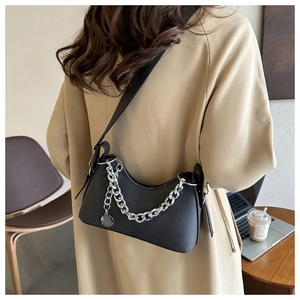 Close-up of black crescent underarm bag with silver chain and metal charm on a model