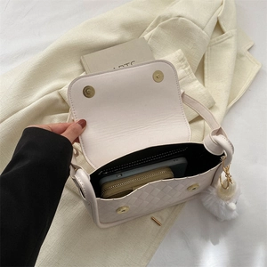 Dettaglio borsa a tracolla trapuntata beige con fibbie magnetiche e ciondolo peluche