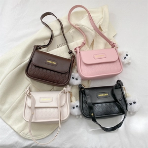 Detail of crossbody bag featuring quilted texture, gold logo and plush monster charm