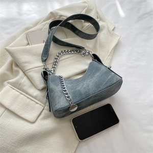 Detailed view of grey-blue textured shoulder bag with silver chain and a phone for scale