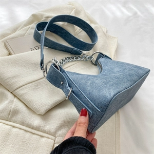 Detail of dark blue vintage textured bag with bold silver chain and wide strap
