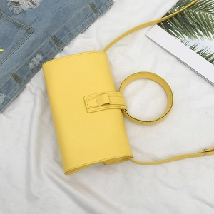 Dettaglio di una borsa a tracolla rettangolare giallo brillante con manico tondo su sfondo