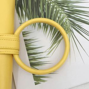 Dettaglio di una borsa a busta giallo brillante con grande manico tondo e cuciture pulite
